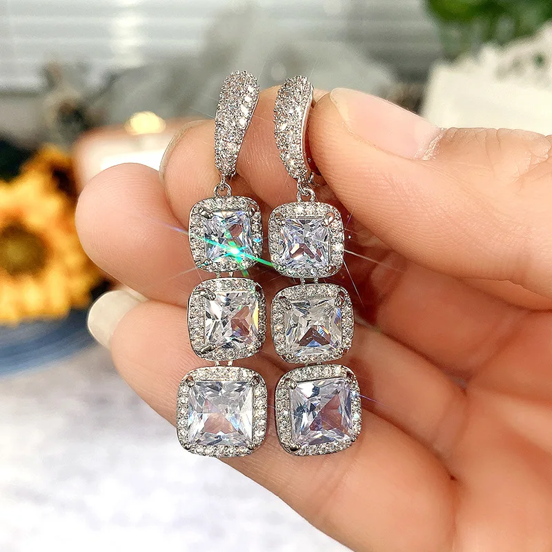 Square drop earrings held in hand showing size