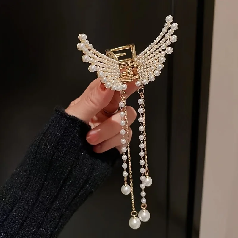 Butterfly hair claw clip held in hand showing pearl tassels